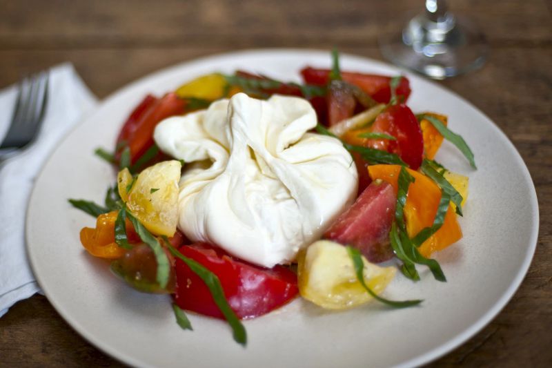 Một viên burrata làm tâm điểm của dĩa salad cà chua